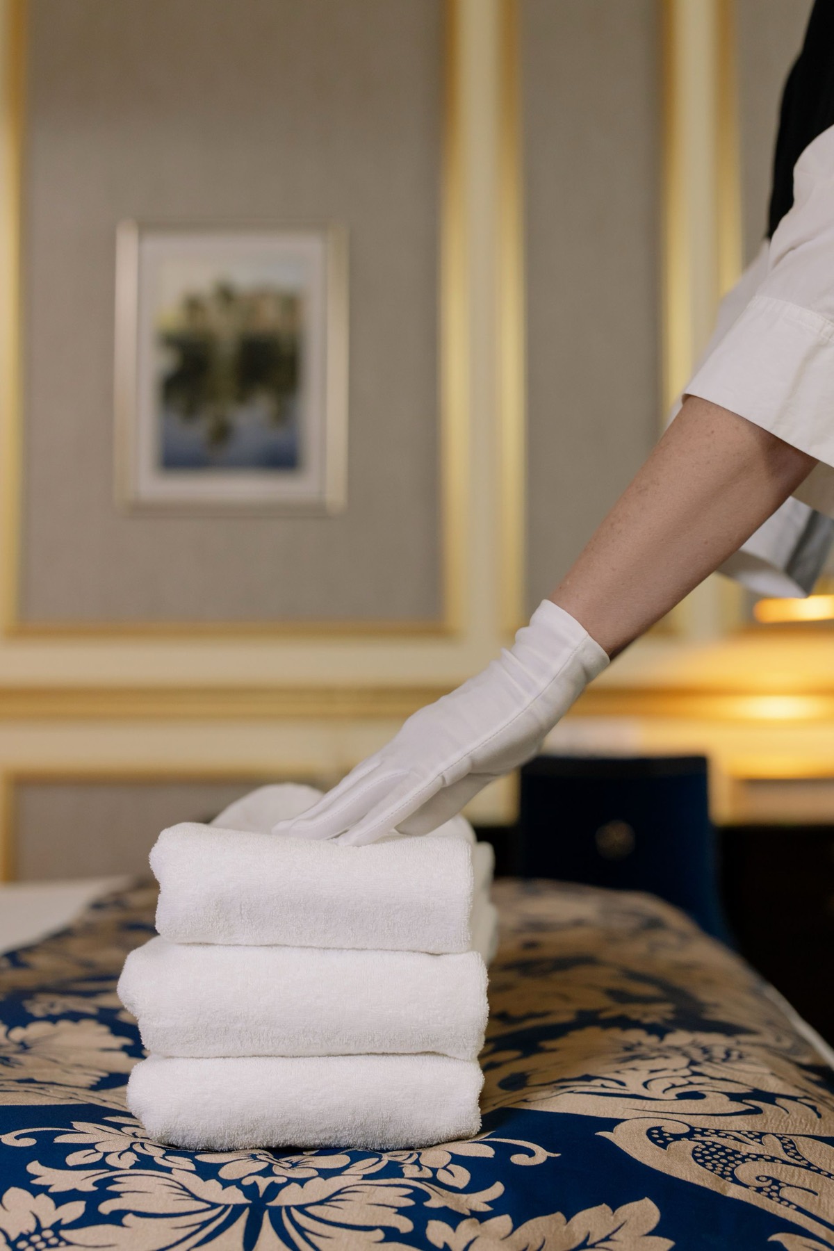 Housekeeping placing pressed towels on a dressed hotel bed